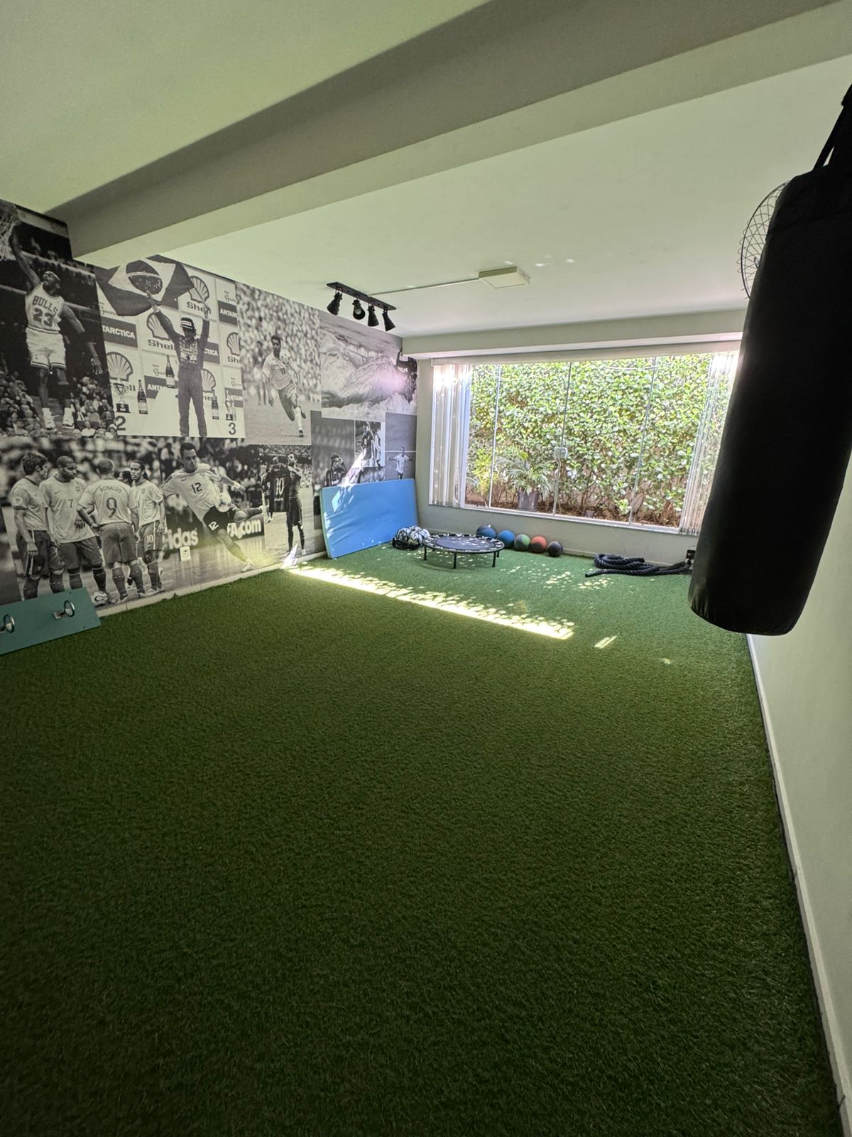 Sala de treino funcional com grama sintética, saco de pancada e medicine balls