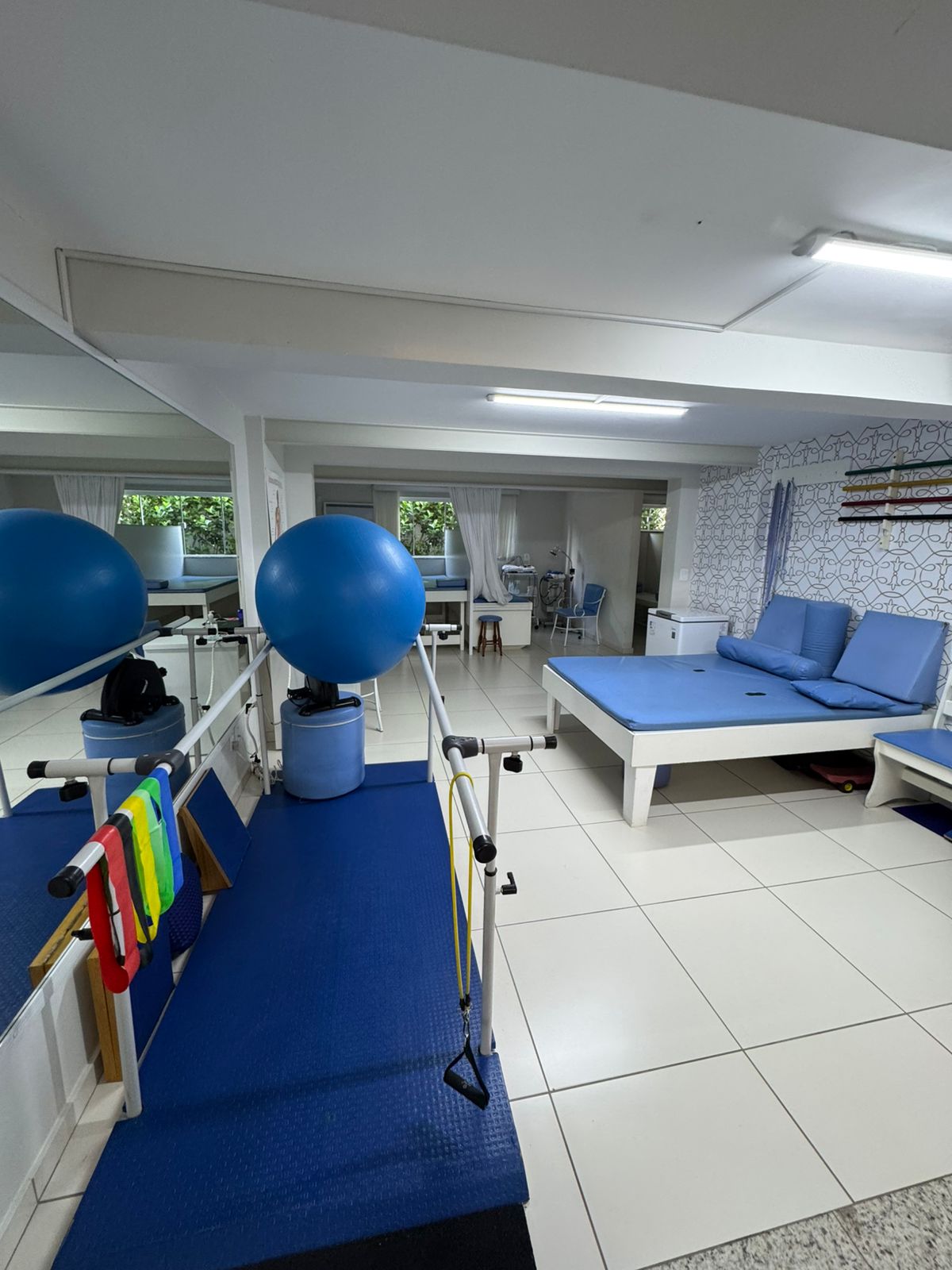 Sala de fisioterapia com barras paralelas, macas e bolas suíças